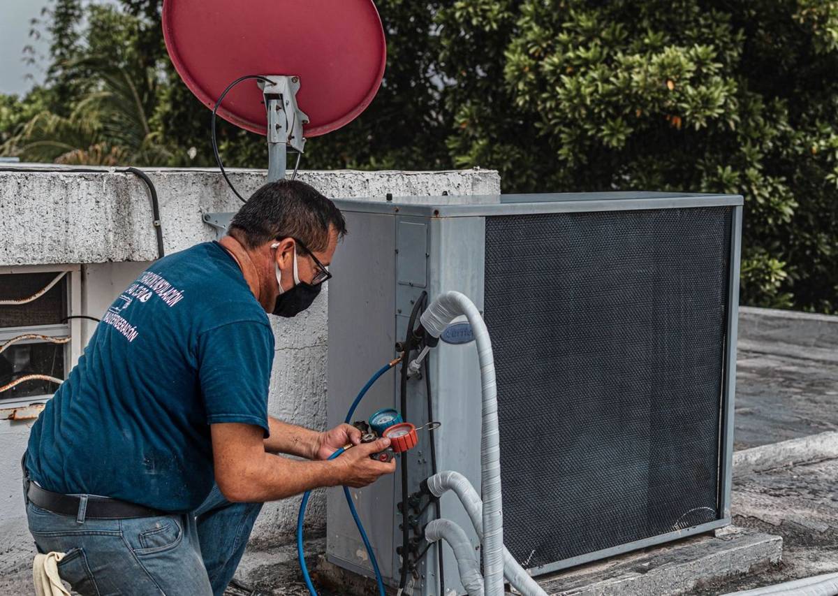 A technician servicing an outdoor air conditioning unit